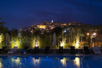 Illuminated buildings by swimming pool at night