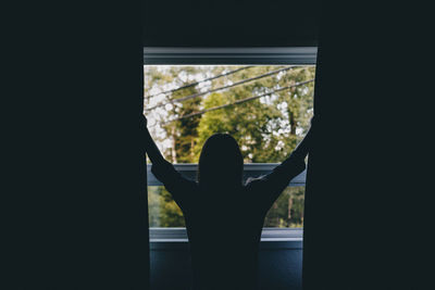 Rear view of man looking through window