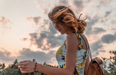 Woman standing against sky during sunset