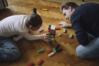 High angle view of father and daughter playing toy blocks on floor at home