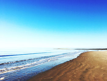 Scenic view of beach against clear blue sky