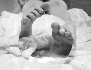 Close-up of hands lying on bed