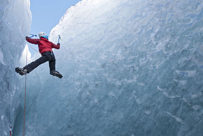 Woman climbing out of glacier cave / sólheimajökull glacier in iceland