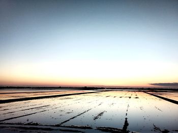 Scenic view of snow covered land against clear sky during sunset