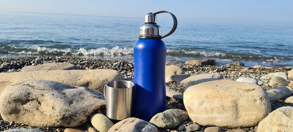 Deck chairs on rocks by sea against sky