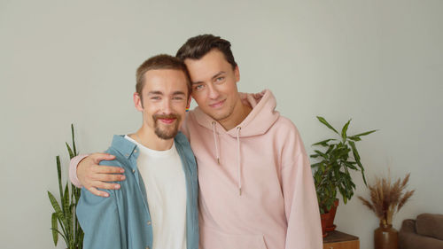 Portrait of smiling couple standing against wall