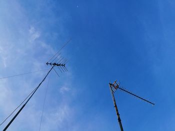 Low angle view of telephone poles against blue sky