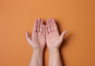 Two female hands on a brown background. empty palms open, top view person