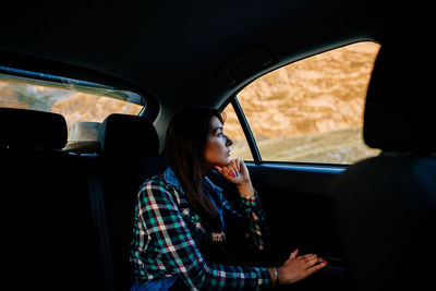 Side view of woman sitting in car