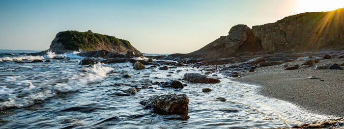 Rocks in sea against sky during sunset