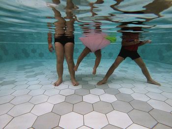 Low section of women standing on swimming pool