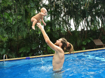 Father throwing daughter while swimming in pool