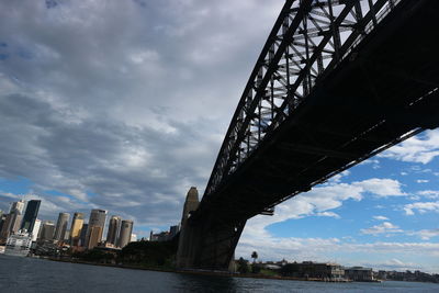 Low angle view of bridge over river and buildings against sky