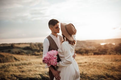 Couple kissing on field against sky