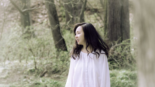 Young woman standing against trees