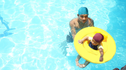 High angle view of father and son swimming in pool