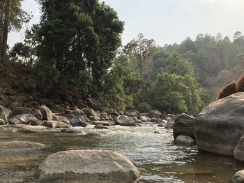 View of river flowing through rocks against sky