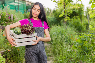 Portrait of young woman standing by plants