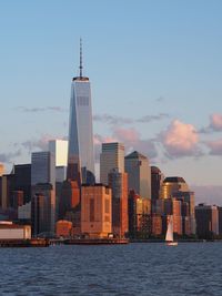 River by one world trade center with cityscape against sky