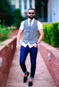 Full length portrait of young man standing on footpath