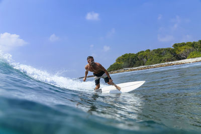 Full length of man surfing in sea against sky