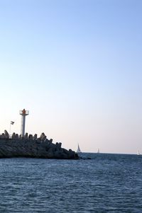 Sailboats on sea against clear sky