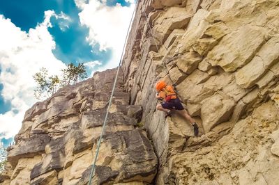 Low angle view of person on rock against sky