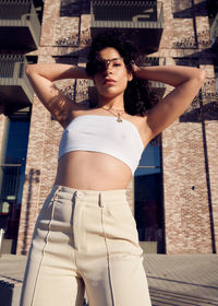 Portrait of young woman standing against wall