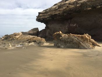 Rock formation on beach against sky