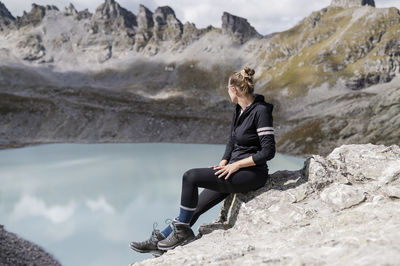 Young hiker sitting on rock looking at mountain