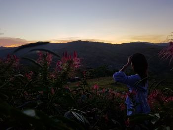 Rear view of person on field against sky during sunset