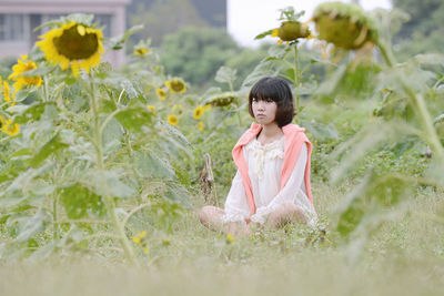 Young woman sitting amidst plants on field