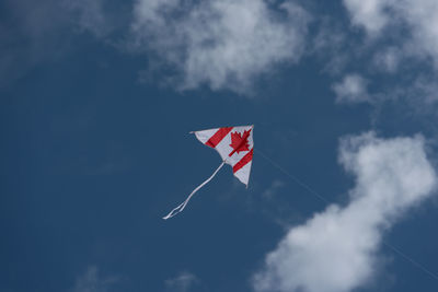 Low angle view of canadian flag kite flying against sky