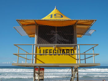 Lifeguard hut on beach against clear blue sky