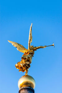 Low angle view of angel statue against blue sky