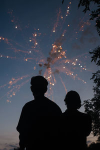 Rear view of silhouette people standing against sky at night