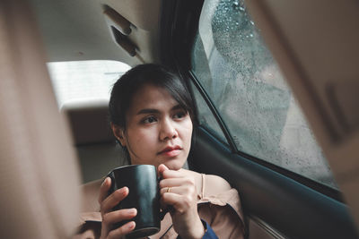 Woman drinking coffee while sitting in car