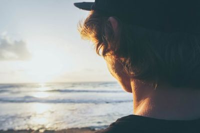 Rear view of young man at beach during sunset