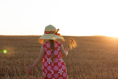 Rear view of woman standing on field against clear sky