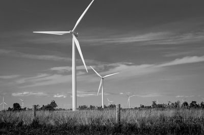 Wind turbines on field against sky