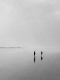 Mid distance view of man and woman at beach during foggy weather