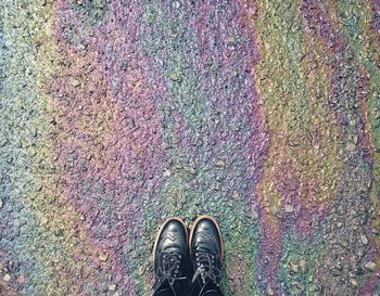 Low section of person wearing shoes on spilled oil