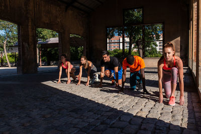 Group of diverse sportspeople standing in crouch start position ready for run during training in urban area of city