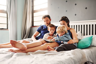 Parents and kids sitting on bed at home