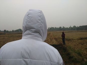Rear view of man standing on field against sky
