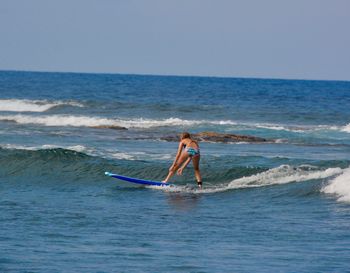Woman surfing in sea against clear sky