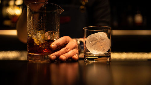 Glass and round ice in the hand of the bartender