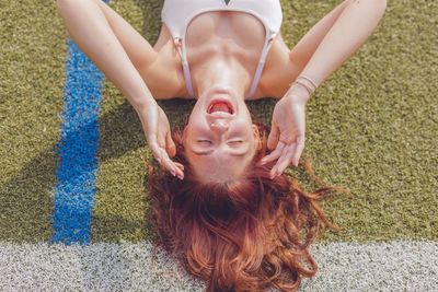Woman screaming while lying on field in sunny day