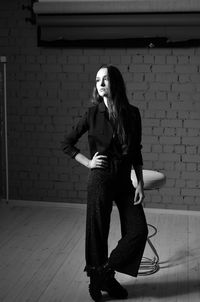 Portrait of young woman standing against brick wall
