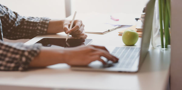 Cropped hand of woman using technology on table